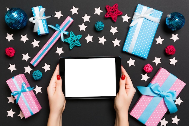 Foto mãos cortadas segurando tablet digital por decorações de natal na mesa