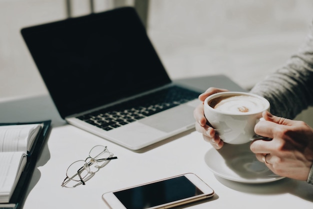 Mãos cortadas tomando café na mesa em um café