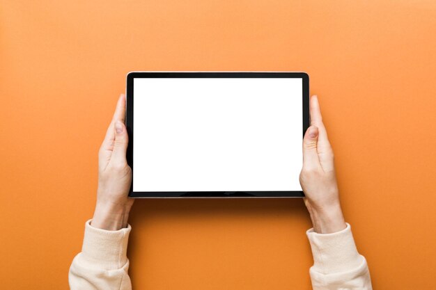 Mãos cortadas usando tablet digital contra fundo amarelo