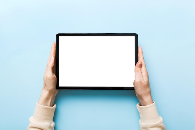 Mãos cortadas usando tablet digital contra fundo azul