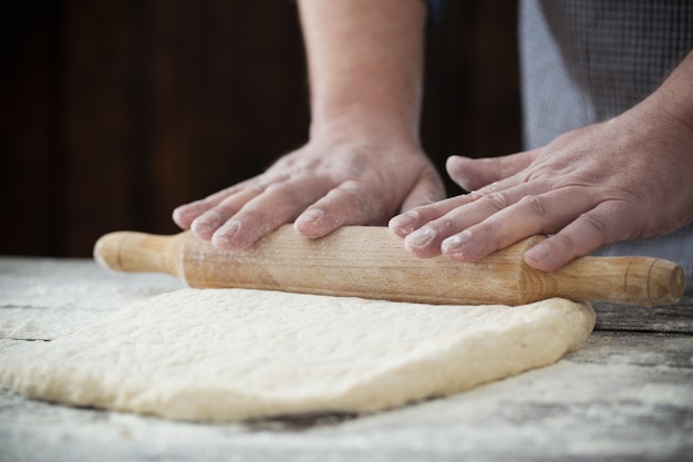 Mãos cozinhar massa na mesa de madeira escura