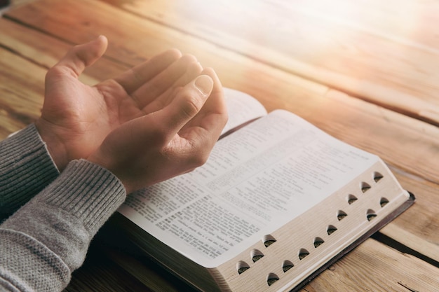 Foto mãos cristãs orando com o livro aberto