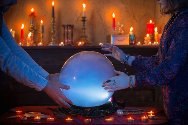 Mãos da cartomante com bola de cristal iluminada