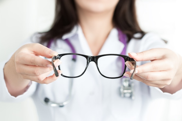 Foto mãos da médica oculista dando um par de óculos escuros. conceito de boa visão