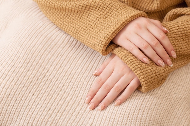 Mãos da mulher com manicure com cobertor de malha