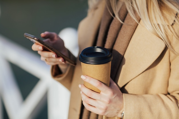 mãos da mulher com smartphone e café