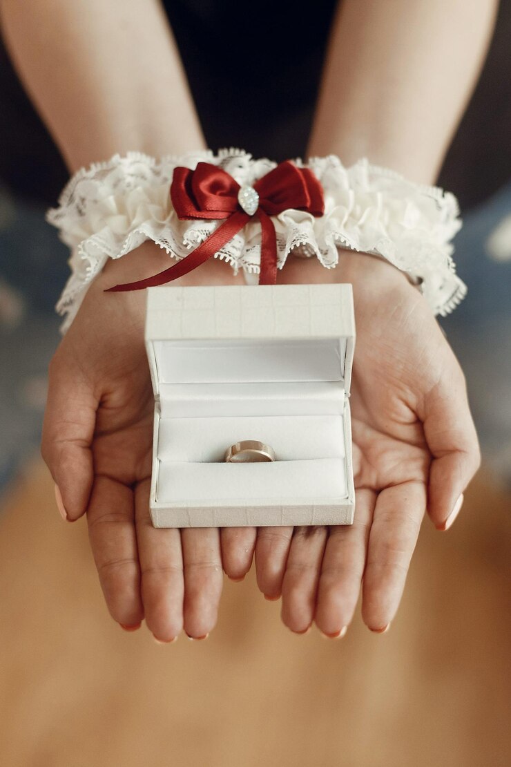 Foto mãos da mulher do conceito da preparação da manhã do casamento na liga de seda que guarda o anel dourado no espaço da caixa para o texto