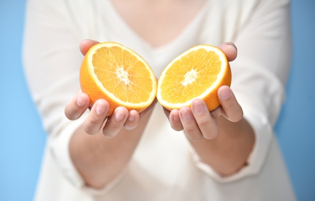 Foto mãos da mulher que guardam a laranja cortada.