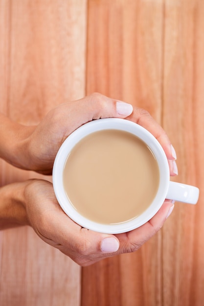 Mãos da mulher segurando xícara de café