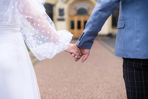 Mãos da noiva e do noivo com anéis noiva e noivo em um café mesa de buquê de casamento noiva e noivo seguram as mãos um do outro Anéis de casamento Casal apaixonado em um café chá quente para amantes