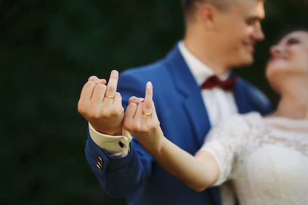 Foto mãos da noiva e do noivo em anéis de casamento. casal mostra seus anéis de brincadeira