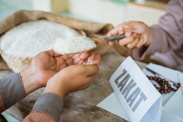 Mãos dando grãos de arroz para zakat ajudando os pobres