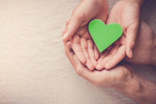 Mãos de adulto e criança segurando coração verde, vegetariano vegan, vida sustentável, bem-estar saudável, conceito de responsabilidade social de RSE, ambiente mundial da, dia mundial da saúde