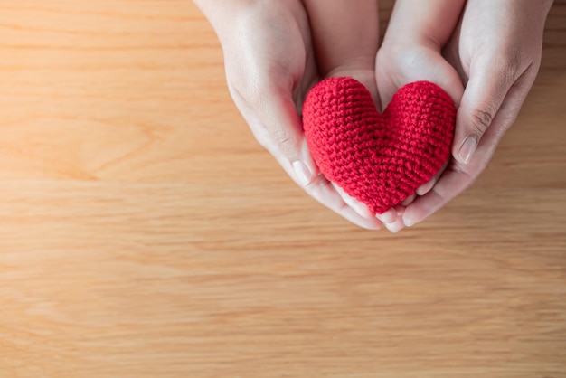 Mãos de adulto e criança segurando um coração vermelho de fio Esperança amor conceito de vida