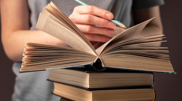 Mãos de aluna segurando lápis e livro de leitura, prepare-se para o exame à mesa à noite. Conceito de educação