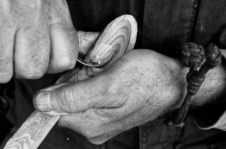 Foto mãos de artesãos - trabalhando em um pedaço de madeira fazendo uma colher