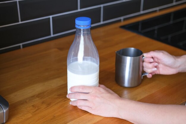 Mãos de barista segurando garrafa de leite e jarro para espumar para café cappuccino