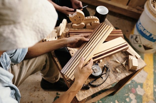 Foto mãos de carpinteiros discutindo pranchas de madeira com listras pintadas com laca