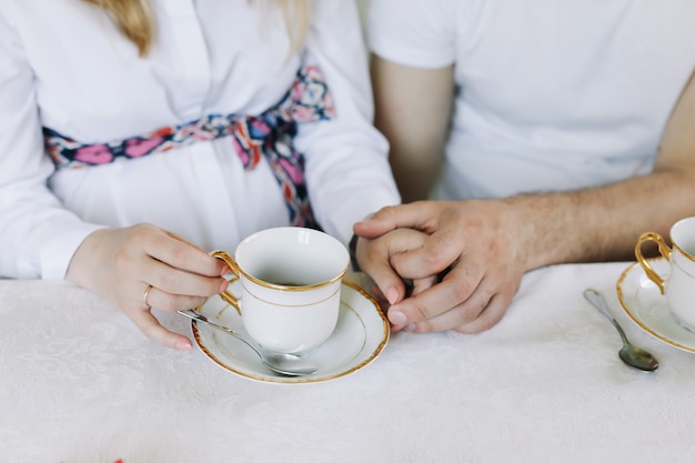 Mãos de casal feliz bebendo chá quente em casa