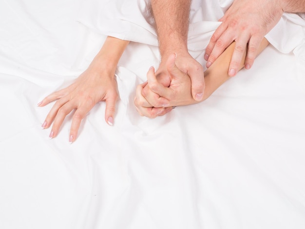 Mãos de casal puxando lençóis brancos no conceito de orgasmo de êxtase de momentos eróticos de orgasmo de paixão