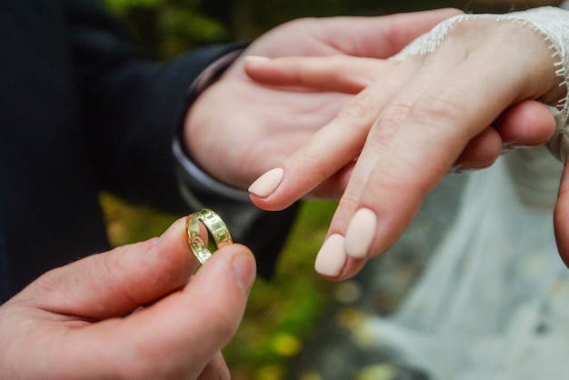 Foto mãos de casamento com anéis. birde usa o anel no dedo do noivo