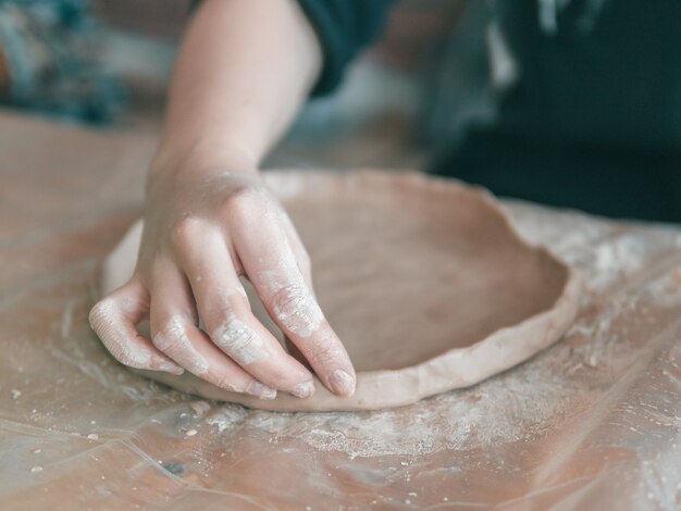 Mãos de Ceramista fazem um prato de barro