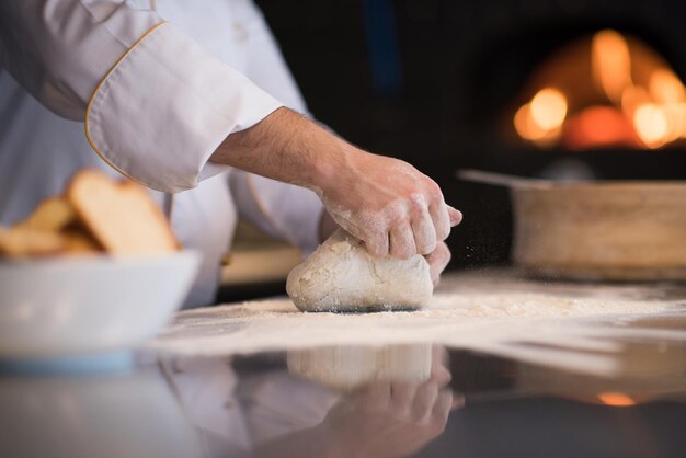 mãos de chef preparando massa para pizza na mesa polvilhada com farinha closeup