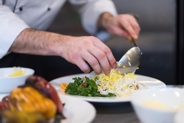 Mãos de chef servindo risoto de vegetais na cozinha do restaurante