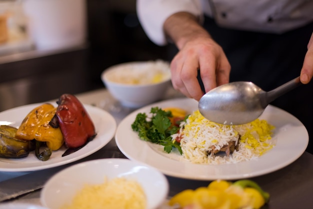 Mãos de chef servindo risoto de vegetais na cozinha do restaurante