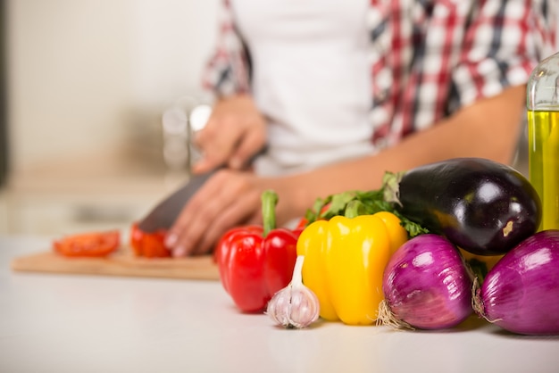 Mãos de close-up de uma mulher que corta legumes.