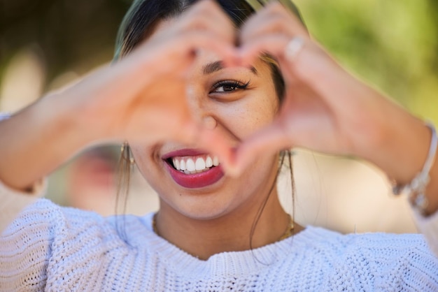 Foto mãos de coração amam e sorriem com retrato de mulher no parque para apoio símbolo de saúde e bondade emoji de paz e motivação com pessoa e gesto na natureza para empatia, confiança e dia dos namorados