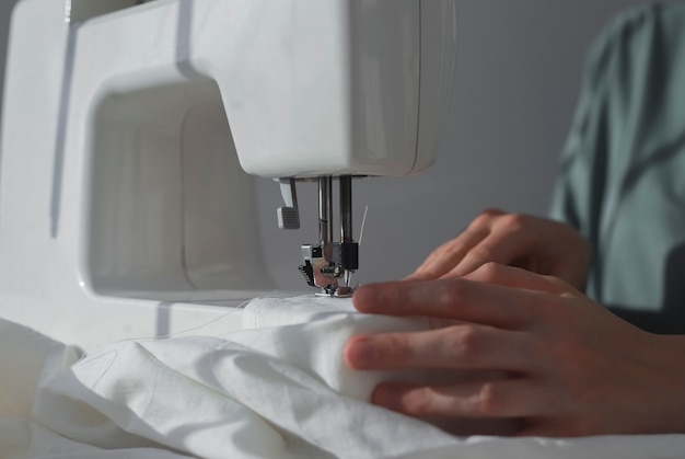 Mãos de costureira com pano de linho no processo de trabalho da máquina de costura com tecido de algodão natural