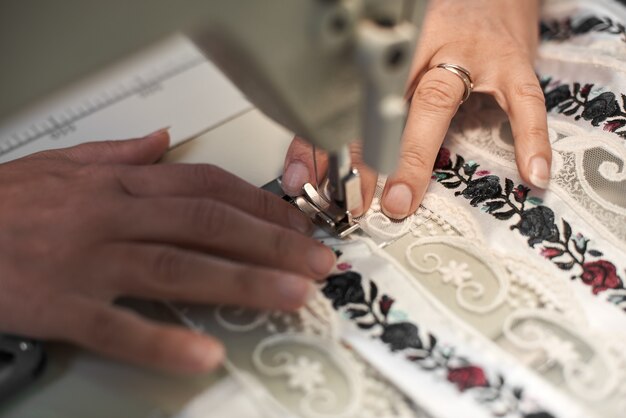 Mãos de costureira costurando em máquina moderna