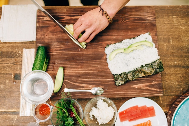 Foto mãos de cozinheiro fazendo rolos de sushi