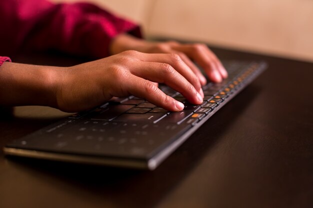 Mãos de criança afro usando o teclado.