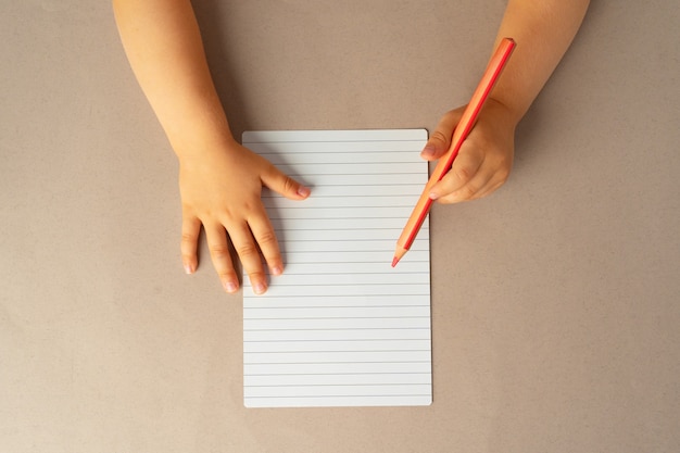 Foto mãos de criança escrevendo em um caderno aberto, vista superior