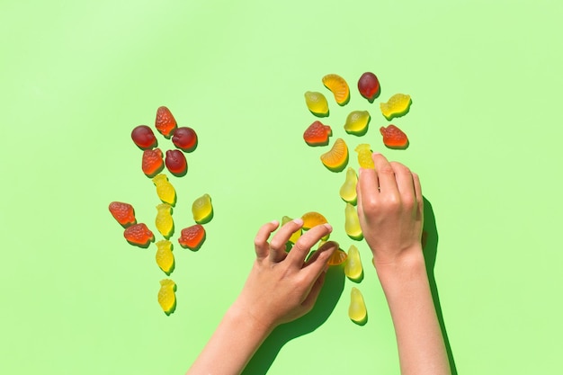 Mãos de criança fazendo flores de balas de gelatina doces em um fundo verde menta Crianças artes e ofícios arte criativa diy divertido auto-conceito de aprendizagem de educação