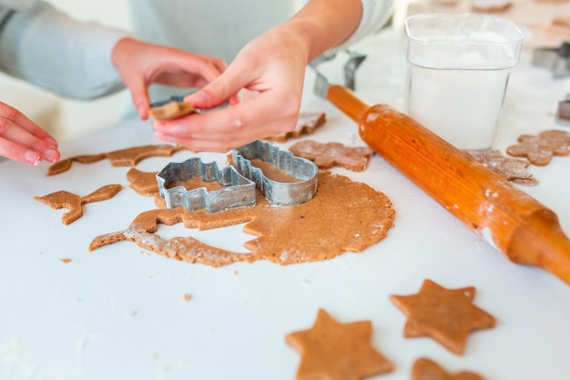 Mãos de criança fazendo pão de mel, cortando biscoitos de massa de pão de mel. Comida festiva, processo de cozimento, culinária familiar, conceito de tradições de Natal e Ano Novo