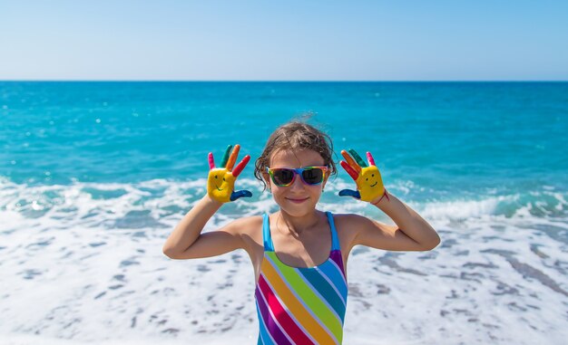 Mãos de criança pintadas com tintas no mar. Foco seletivo. Criança.