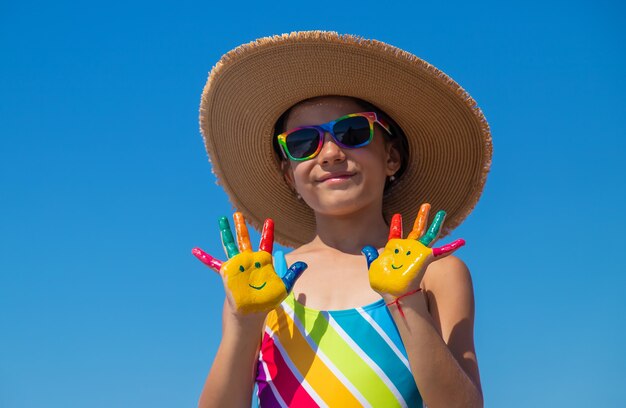 Foto mãos de criança pintadas com tintas no mar. foco seletivo. criança.