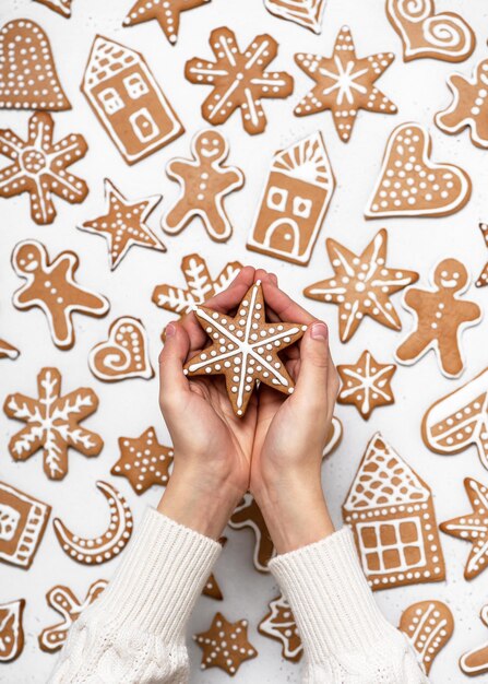 Foto mãos de criança segurando um pão de gengibre de natal feito em casa pintado na forma de uma estrela