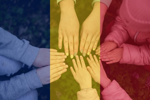 Mãos de crianças no fundo da bandeira da Romênia, patriotismo romeno e conceito de unidade