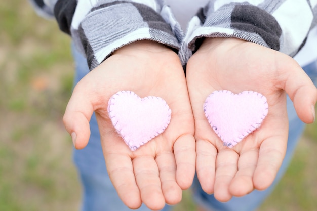 Mãos de crianças segurando corações artesanais