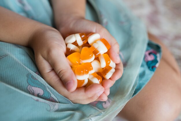 Mãos de crianças segurando doces laranja