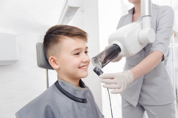 Mãos de dentista fazem imagem de raio-x de mandíbula para garotinho na clínica odontológica