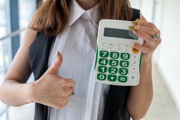 Mãos de empresária seguram calculadora no corredor do escritório. conceito de contabilidade