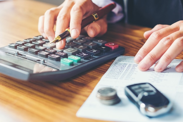 Mãos de empresário com calculadora e custo no escritório e dados financeiros