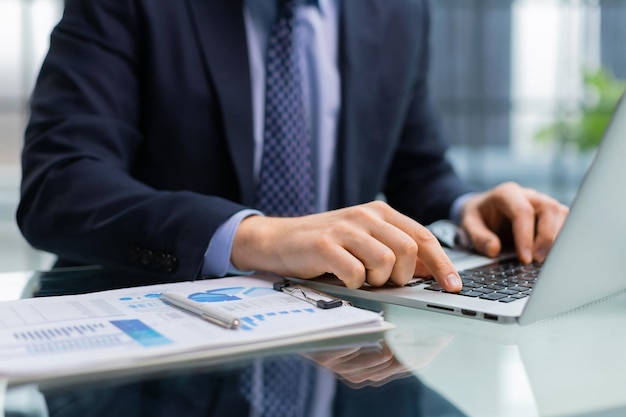 Mãos de empresário digitando no teclado do laptop trabalhando na mesa