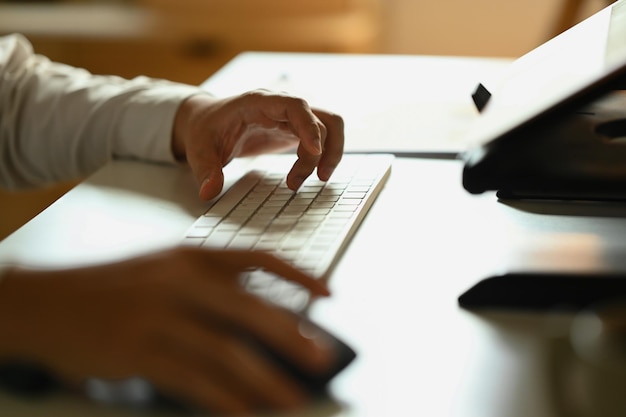 Foto mãos de empresário em close-up digitando no teclado procurando informações ou navegando na internet na mesa