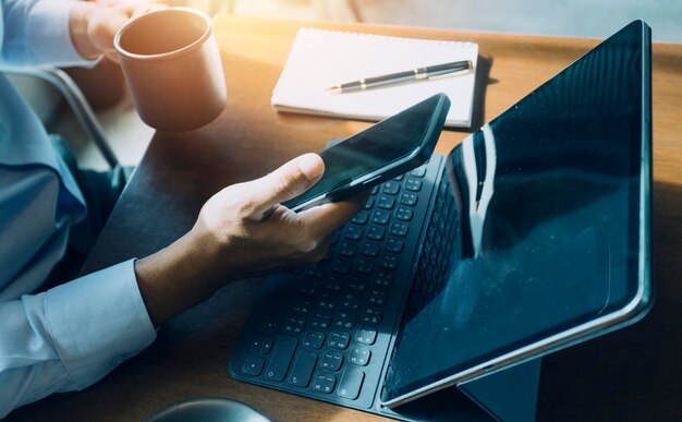 Mãos de empresário trabalhando com finanças sobre custo e calculadora e laptop com smartphone tablet no escritório na luz da manhã